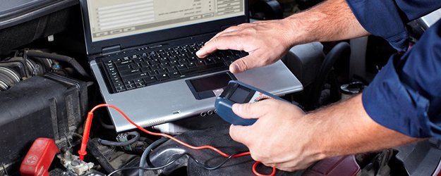 A person using a cell phone to check the battery of a laptop.